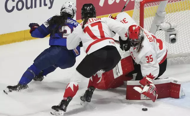 Canada goaltender Ann-Renee Desbiens (35) makes a save against United States' Abbey Murphy (37) as Canada's Ella Shelton (17) skates in to defend during the first period of a hockey game at the IIHF Women's World Hockey Championship in Utica, N.Y., Monday, April 8, 2024. (Christinne Muschi/The Canadian Press via AP)