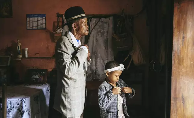 This image provided by World Press Photo and taken by Lee-Ann Olwage for GEO is part of a series titled Valim-babena which won the World Press Photo Story of the Year Award and shows Dada Paul Rakotazandriny (91), who is living with dementia, and his granddaughter, Odliatemix Rafaraniriana (5), get ready for church on Sunday morning at his home in Antananarivo, Madagascar. 12 March 2023. (Lee-Ann Olwage/Geo/World Press Photo via AP)