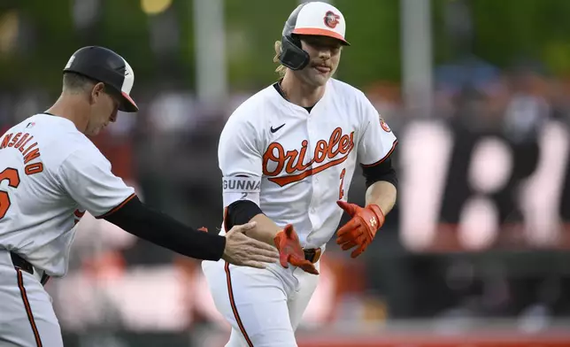 Baltimore Orioles' Gunnar Henderson, right, celebrates after his home run with third base coach Tony Mansolino, left, during the first inning of a baseball game against the New York Yankees, Monday, April 29, 2024, in Baltimore. (AP Photo/Nick Wass)