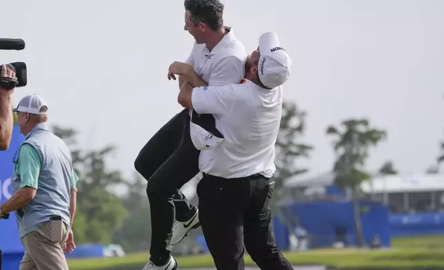Shane Lowry, of Ireland, hoists up teammate Rory McIlroy, of Northern Ireland, after they won the PGA Zurich Classic golf tournament at TPC Louisiana in Avondale, La., Sunday, April 28, 2024. (AP Photo/Gerald Herbert)