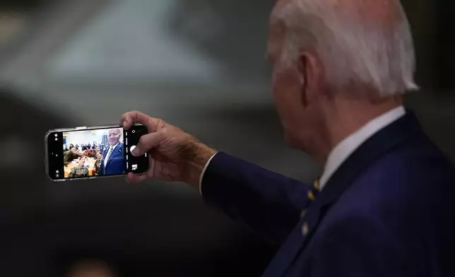 FILE - President Joe Biden takes a selfie at Marine Corps Air Station Cherry Point in Havelock, N.C., Monday, Nov. 21, 2022, at a Thanksgiving dinner with members of the military and their families. Democrats are wrestling with how to deploy generative AI. Still smarting from being outmaneuvered on social media by Donald Trump and his allies in 2016, Democratic strategists say they are nevertheless treading carefully in embracing artificial intelligence tool that disinformation experts say could pose a threat to democracy. (AP Photo/Patrick Semansky, File)