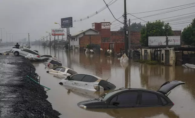 Vehicles are partially submerged on a street flooded by heavy rains in Sao Leopoldo, Rio Grande do Sul state, Brazil, Saturday, May 11, 2024. (AP Photo/Andre Penner)