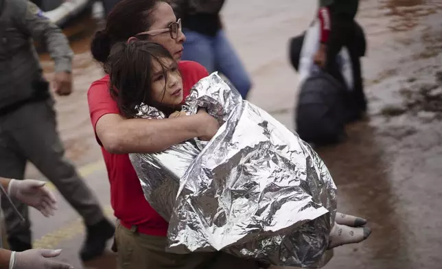 A firefighter carries a girl rescued from an area flooded by heavy rains in Porto Alegre, Rio Grande do Sul state, Brazil, Saturday, May 4, 2024. (AP Photo/Carlos Macedo)