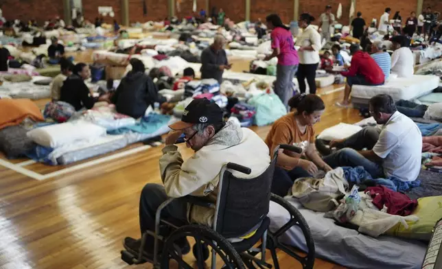 People rest in a shelter after their homes were flooded by heavy rains in Porto Alegre, Rio Grande do Sul state, Brazil, Saturday, May 4, 2024. (AP Photo/Carlos Macedo)