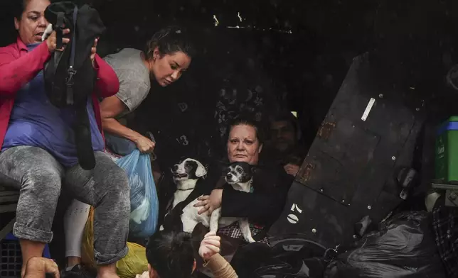 Residents and their pets evacuate a flooded area after heavy rain in Sao Sebastiao do Cai, Rio Grande do Sul state, Brazil, Thursday, May 2, 2024. (AP Photo/Carlos Macedo)