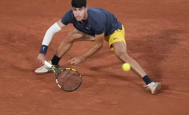 Spain's Carlos Alcaraz slides to play shot against Jeffrey John Wolf of the U.S. during their first round match of the French Open tennis tournament at the Roland Garros stadium in Paris, Sunday, May 26, 2024. (AP Photo/Christophe Ena)