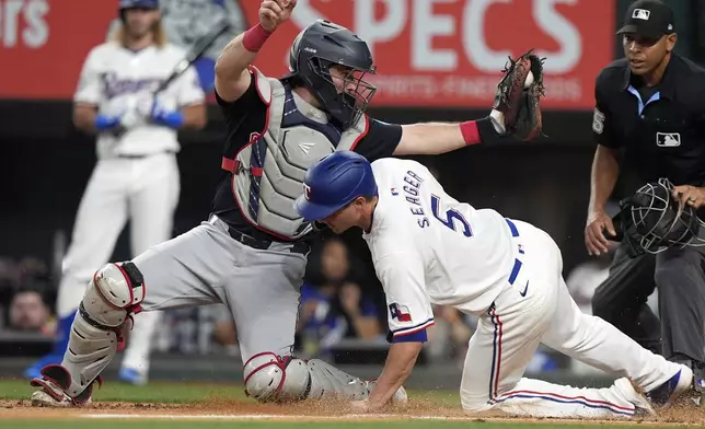 Texas Rangers' Corey Seager (5) is caught out by Cleveland Guardians catcher Austin Hedges, left, for a bases loaded double play ending the fourth inning of a baseball game in Arlington, Texas, Wednesday, May 15, 2024. (AP Photo/LM Otero)