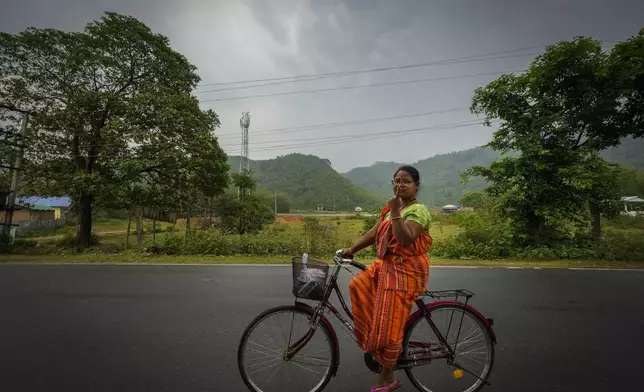 Purnima Boro, 30, a Bodo tribal woman in traditional attire riding a bicycle shows the indelible ink mark on her index finger as she returns after casting her vote during the third phase of general election on the outskirts of Guwahati, India, Tuesday, May 7, 2024. (AP Photo/Anupam Nath)