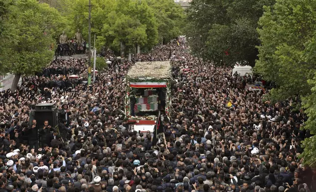 In this photo released by the Iranian Presidency Office, mourners gather around a truck carrying the flag-draped coffins of President Ebrahim Raisi and his companions who were killed in a helicopter crash on Sunday in a mountainous region of the country's northwest, in their funeral ceremony in the city of Tabriz, Iran, Tuesday, May 21, 2024. (Iranian Presidency Office via AP)
