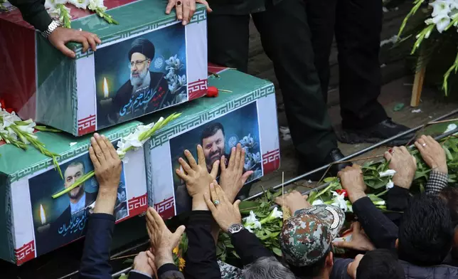 In this photo provided by Fars News Agency, mourners try to touch the coffins of Iranian President Ebrahim Raisi, top, Foreign Minister Hossein Amirabdollahian, left, and Raisi's chief bodyguard Gen. Mehdi Mousavi, who were killed in a helicopter crash on Sunday in a mountainous region of the country's northwest, during a funeral ceremony at the city of Tabriz, Iran, Tuesday, May 21, 2024. Mourners in black began gathering Tuesday for days of funerals and processions for Iran's late president, foreign minister and others killed in a helicopter crash, a government-led series of ceremonies aimed at both honoring the dead and projecting strength in an unsettled Middle East. (Ata Dadashi, Fars News Agency via AP)