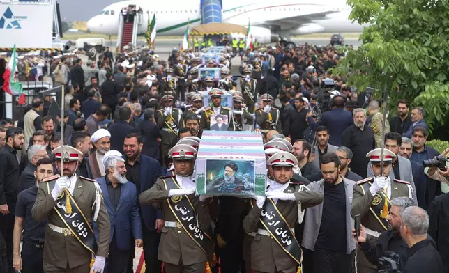 In this photo released by the Iranian Presidency Office, army members carry the flag-draped coffins of President Ebrahim Raisi and his companions who were killed in a helicopter crash on Sunday in a mountainous region of the country's northwest, during a funeral ceremony at Mehrabad airport in Tehran, Iran, Tuesday, May 21, 2024. (Iranian Presidency Office via AP)