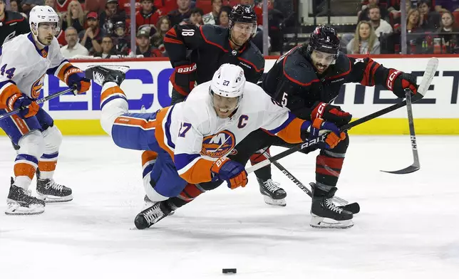 Carolina Hurricanes' Jalen Chatfield (5) battles with New York Islanders' Anders Lee (27) for the puck during the first period in Game 5 of an NHL hockey Stanley Cup first-round playoff series in Raleigh, N.C., Tuesday, April 30, 2024. (AP Photo/Karl B DeBlaker)
