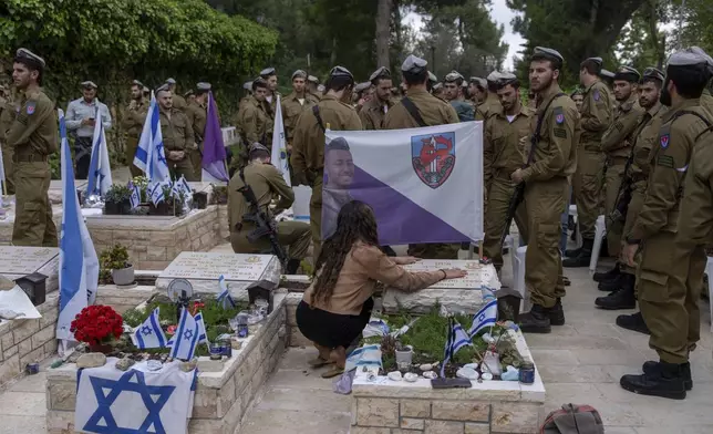 Israeli soldiers and family members of fallen soldiers visit their graves on the eve of the country's annual Memorial Day for fallen soldiers and victims of nationalistic attacks at Mount Herzl military cemetery in Jerusalem, Sunday, May 12, 2024. (AP Photo/Ohad Zwigenberg)