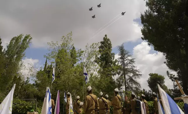 Israeli fighter jets fly over soldiers standing next to comrades graves during a rehearsal on the eve of the country's Memorial Day for fallen soldiers at the Mount Herzl military cemetery in Jerusalem, Sunday, May 12, 2024. (AP Photo/Ohad Zwigenberg)