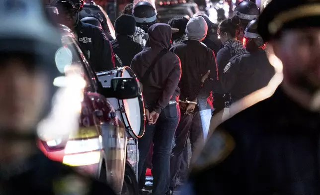 New York City police officers take people into custody near the Columbia University campus in New York Tuesday, April 30, 2024, after a building taken over by protesters earlier in the day was cleared, along with a tent encampment. (AP Photo/Craig Ruttle)