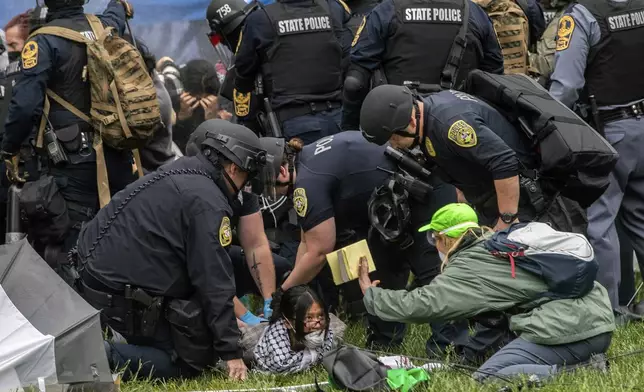 Police with riot shields detain a pro-Palestinian demonstrator on the ground as a National Lawyers Guild representative holds up an emergency contact notebook, on the University of Virginia campus, in Charlottesville, Va., where tents are set up, Saturday, May 4, 2024. (Cal Cary/The Daily Progress via AP)
