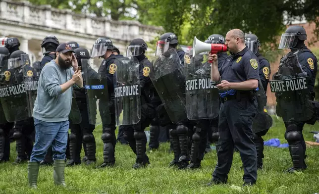 Police use a microphone as a pro-Palestinian demonstrator listens on the grounds of the University of Virginia, in Charlottesville, Va., where tents were set up, Saturday, May 4, 2024. (Cal Cary/The Daily Progress via AP)