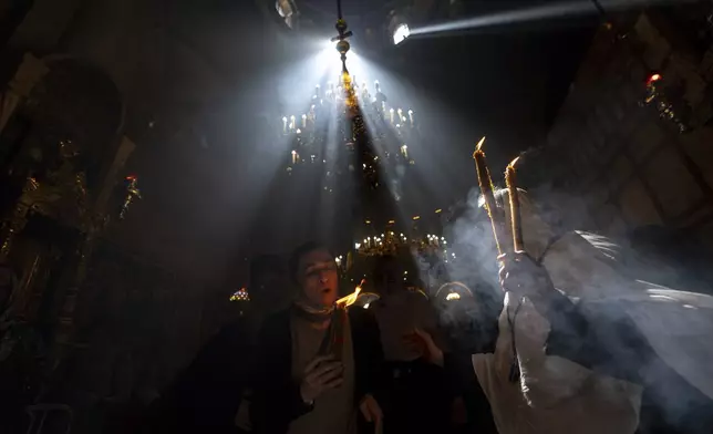 Christian pilgrims hold candles as they gather during the ceremony of the Holy Fire at the Church of the Holy Sepulchre, where many Christians believe Jesus was crucified, buried and rose from the dead, in the Old City of Jerusalem, Saturday, May 4, 2024. (AP Photo/Ohad Zwigenberg)