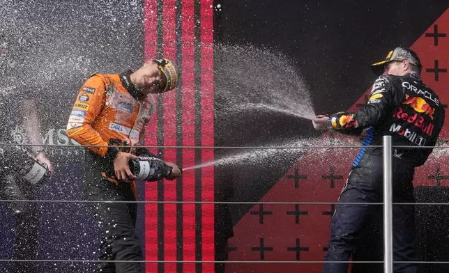 second placed McLaren driver Lando Norris of Britain, left, celebrates on the podium with winner Red Bull driver Max Verstappen of the Netherlands after the Italy's Emilia Romagna Formula One Grand Prix race at the Dino and Enzo Ferrari racetrack in Imola, Italy, Sunday, May 19, 2024. (AP Photo/Luca Bruno)