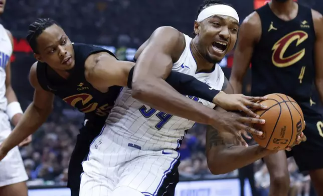 Orlando Magic center Wendell Carter Jr. (34) controls a rebound against Cleveland Cavaliers forward Isaac Okoro during the first half of Game 5 of an NBA basketball first-round playoff series, Tuesday, April 30, 2024, in Cleveland. (AP Photo/Ron Schwane)