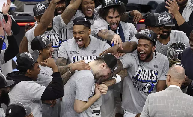 Dallas Mavericks guard Luka Doncic, center, celebrates with teammates after Game 5 of the Western Conference finals in the NBA basketball playoffs against the Minnesota Timberwolves, Thursday, May 30, 2024, in Minneapolis. The Mavericks won 124-103, taking the series 4-1 and moving on to the NBA Finals. (AP Photo/Matt Krohn)