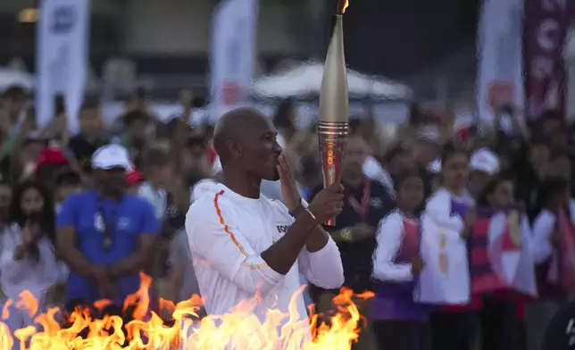 Torchbearer Didier Drogba of France holds the Olympic torch after lighting the cauldron at the Velodrome stadium in Marseille, southern France, Thursday, May 9, 2024. Torchbearers are to carry the Olympic flame through the streets of France's southern port city of Marseille, one day after it arrived on a majestic three-mast ship for the welcoming ceremony. (AP Photo/Daniel Cole)