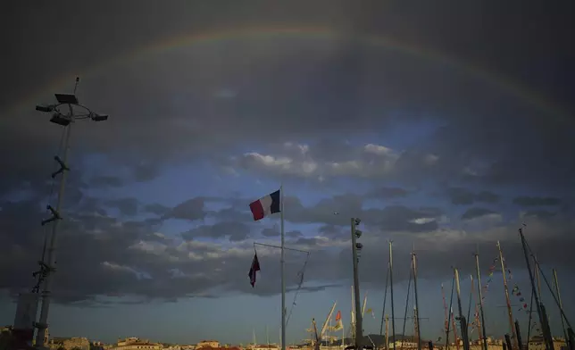 A rainbow rises over the Old Port as the Belem, the three-masted sailing ship which is carrying the Olympic flame, arrives in Marseille, southern France, Wednesday, May 8, 2024. The torch was lit in Greece last month before it was officially handed to France. The Paris 2024 Olympic Games will run from July 26 to Aug.11, 2024. (AP Photo/Daniel Cole)