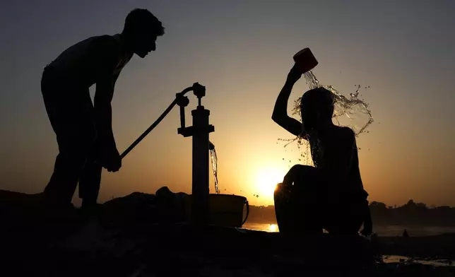 A Pakistani youth, right, cools off under a hand pump at sunset during hot weather in Lahore, Pakistan, Tuesday, May 28, 2024. (AP Photo/K.M. Chaudary)