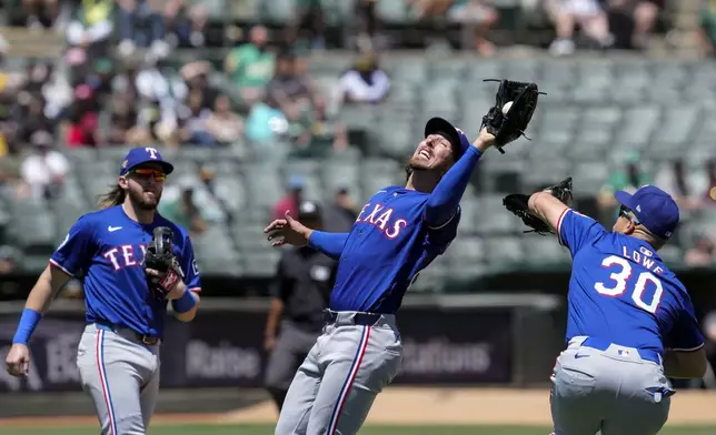 Texas Rangers pitcher Michael Lorenzen, center, catches a pop-up hit by Oakland Athletics' Esteury Ruiz during the second inning in the first baseball game of a doubleheader Wednesday, May 8, 2024, in Oakland, Calif. (AP Photo/Godofredo A. Vásquez)