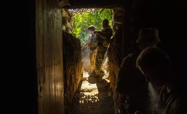 Ukrainian army 59th Separate Motorized Infantry Brigade servicemen Oleksandr, left, and Vitalii smoke cigarettes in a trench outside their dugout, in Avdiivka direction, Ukraine, Monday, May 6, 2024. (AP Photo/Francisco Seco)