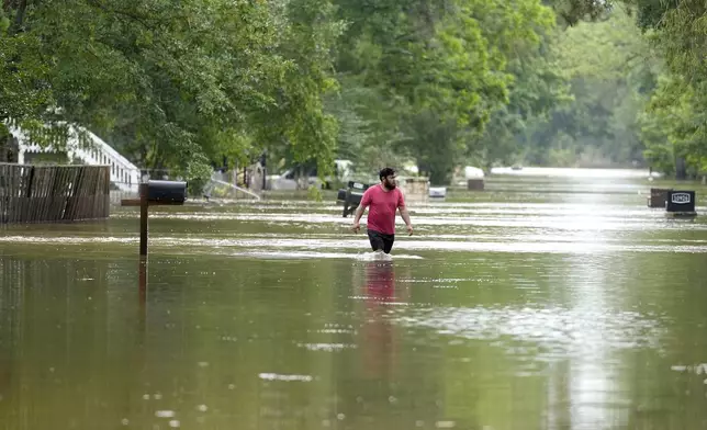 A man walks through floodwaters on River Oaks Drive, Saturday, May 4, 2024, in Woodlock, Texas. (/Houston Chronicle via AP)