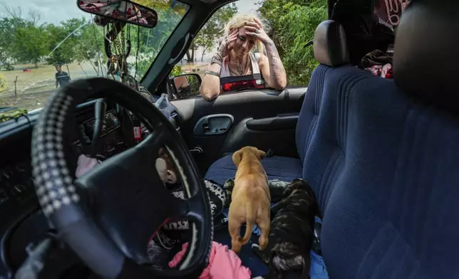 A woman, who only gave her name as Lisamarie, checks on two of her puppies after her neighborhood was evacuated due to severe flooding on Saturday, May 4, 2024, in Channelview, Texas. (Raquel Natalicchio/Houston Chronicle via AP)