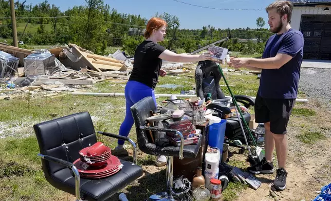 Haley Loukota, left, and her fiance Devin Johnson collect their belongings from storm debris after their home was demolished along Barnsley Loop, Tuesday, May 28, 2024, in Madisonville, Ky. A series of powerful storms hit the central and southern U.S. over the Memorial Day holiday weekend. (AP Photo/George Walker IV)