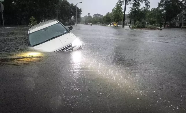 An SUV is stranded in a ditch in a stretch of street flooding during a severe storm, Thursday, May 2, 2024, in Spring, Texas. (Brett Coomer/Houston Chronicle via AP)