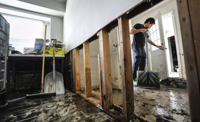 Anthony Dusauzay shovels debris in the laundry room of his flood-damaged home as he works to clean it up in the River Plantation neighborhood on Monday, May 6, 2024, in Conroe, Texas. (Brett Coomer/Houston Chronicle via AP)