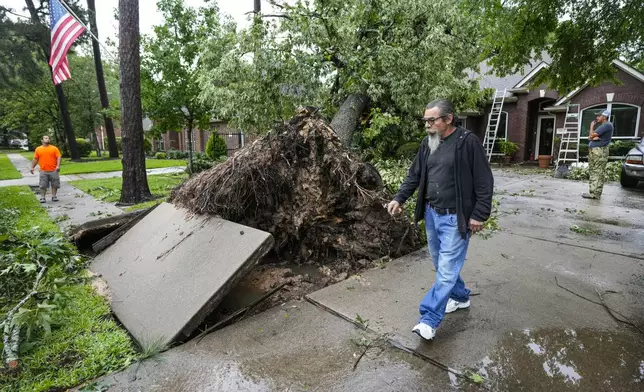 Family members survey the damage after a tree fell on the home of Monica Ramirez during a severe storm, Thursday, May 2, 2024, in Spring, Texas. (Brett Coomer/Houston Chronicle via AP)