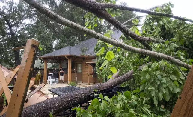Summer Belson, left, and her brother, Steve Brown, survey damage from a fallen tree in Belson's backyard during a severe storm, Thursday, May 2, 2024, in Spring, Texas. (Brett Coomer/Houston Chronicle via AP)