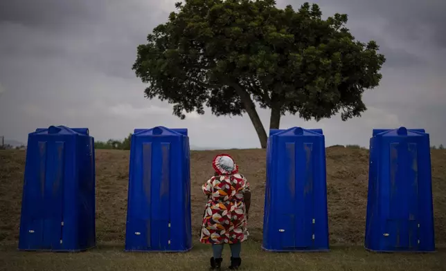 A woman waits to enter a portable public restroom during an election meeting organized by Ukhonto weSizwe party in Mpumalanga, near Durban, South Africa, Saturday, May 25, 2024, ahead of the 2024 general elections scheduled for May 29. (AP Photo/Emilio Morenatti)