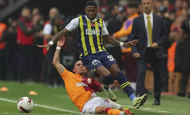 Galatasaray's Lucas Torreira, left, slides for the ball against Fenerbahce's Fred, during a Turkish Super Lig soccer match between Galatasaray and Fenerbahce in Istanbul, Turkey, Sunday, May 19, 2024. (AP Photo)