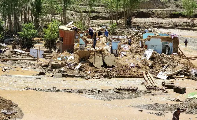 Afghan men collect their belongings from their damaged homes after heavy flooding in Ghor province in western Afghanistan, Saturday, May 18, 2024. Flash floods from heavy seasonal rains in Ghor province killed dozens of people and dozens remain missing, a Taliban official said on Saturday, adding the death toll was based on preliminary reports and might rise. (AP Photo/Omid Haqjoo)