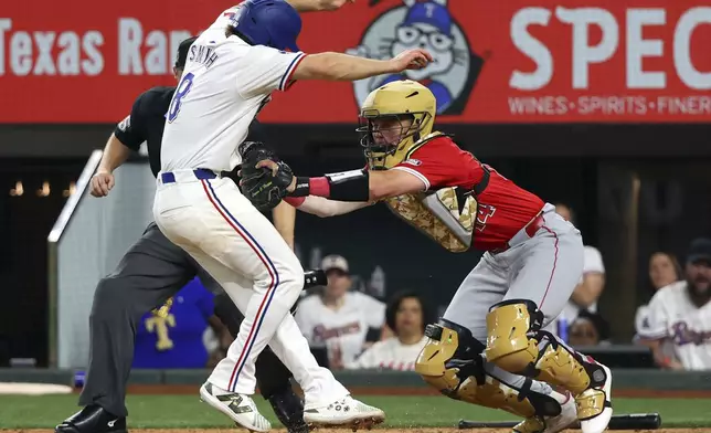 Texas Rangers' Josh Smith (8) is tagged out at the plate by Los Angeles Angels catcher Logan O'Hoppe (14) in the tenth inning of a baseball game Saturday, May 18, 2024, in Arlington, Texas. (AP Photo/Richard W. Rodriguez)
