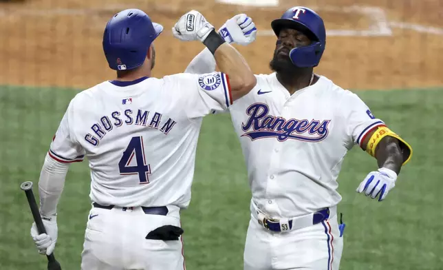 Texas Rangers Robbie Grossman (4) celebrates the home run by Adolis Garcia, right, against the Los Angeles Angels in the sixth inning of a baseball game Saturday, May 18, 2024, in Arlington, Texas. (AP Photo/Richard W. Rodriguez)