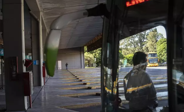 A driver stands inside a bus at the Retiro long-distance bus terminal that is empty due to a general strike against the reforms of President Javier Milei in Buenos Aires, Argentina, Thursday, May 9, 2024. (AP Photo/Rodrigo Abd)