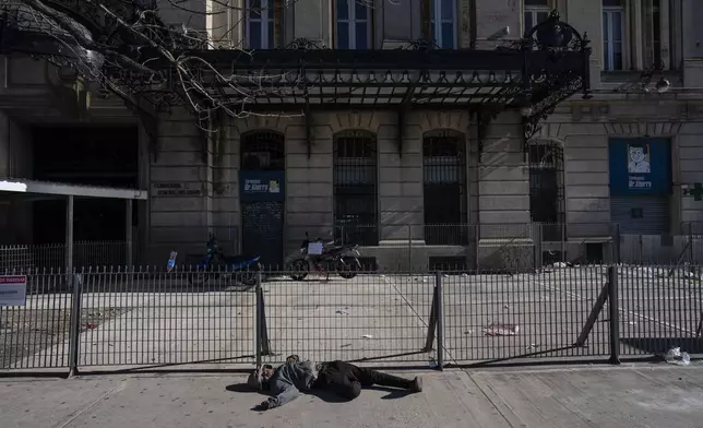 A person sleeps outside the Retiro train station that is empty due to a general strike against the reforms of President Javier Milei in Buenos Aires, Argentina, Thursday, May 9, 2024. (AP Photo/Rodrigo Abd)