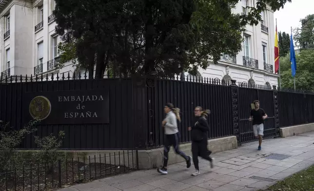 People jog past Spain's embassy in the Palermo neighborhood of Buenos Aires, Argentina, Tuesday, May 21, 2024. A diplomatic crisis between historic allies Spain and Argentina expanded Tuesday as Spain announced the official withdrawal of its ambassador. (AP Photo/Rodrigo Abd)