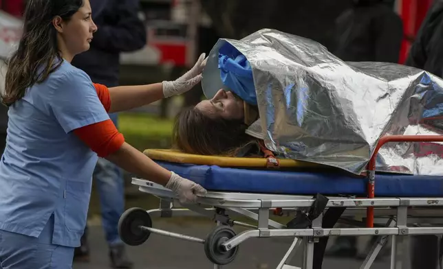 A paramedic transports an injured commuter after two trains collided in Buenos Aires, Argentina, Friday, May 10, 2024. (AP Photo/Natacha Pisarenko)