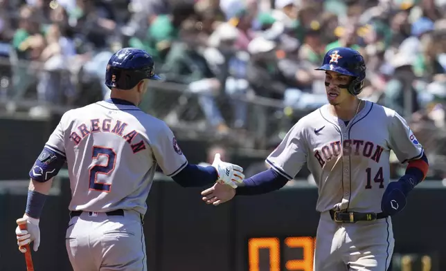 Houston Astros' Mauricio Dubón, right, celebrates with Alex Bregman after scoring against the Oakland Athletics on Kyle Tucker's sacrifice fly during the sixth inning of a baseball game Saturday, May 25, 2024, in Oakland, Calif. (AP Photo/Godofredo A. Vásquez)
