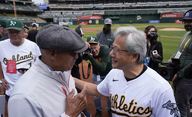NVIDIA founder Jensen Huang, right, speaks with former MLB player Reggie Jackson, front left, during Taiwanese Heritage Day before a baseball game between the Oakland Athletics and the Houston Astros, Saturday, May 25, 2024, in Oakland, Calif. (AP Photo/Godofredo A. Vásquez)