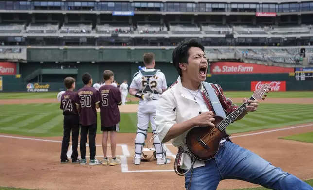 Feng E performs the national anthem on his ukulele during Taiwanese Heritage Day before a baseball game between the Oakland Athletics and the Houston Astros, Saturday, May 25, 2024, in Oakland, Calif. (AP Photo/Godofredo A. Vásquez)