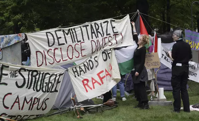 People arrange banners at a pro-Palestinians protest camp at the Vienna University Campus in Vienna, Austria, Tuesday, May 7, 2024. (AP Photo/Heinz-Peter Bader)
